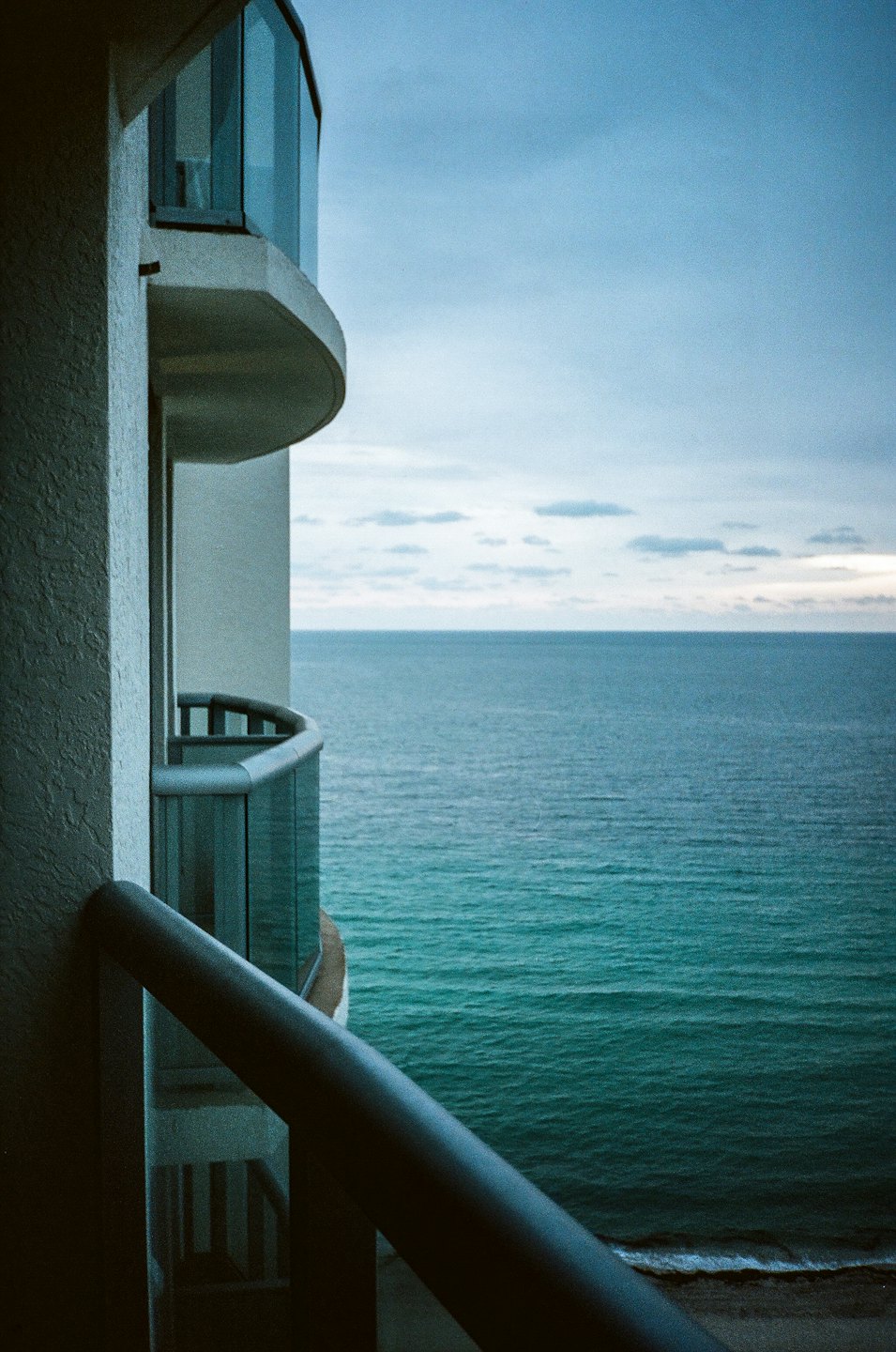 Modern concrete balcony overlooking the vast blue ocean.