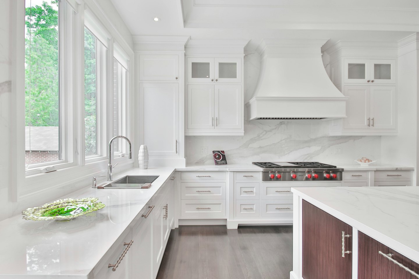 Modern kitchen with white marble countertops and stainless steel range.